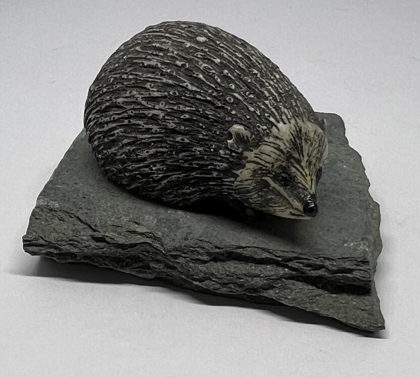 Sculpted hedgehog figurine on a slate base.