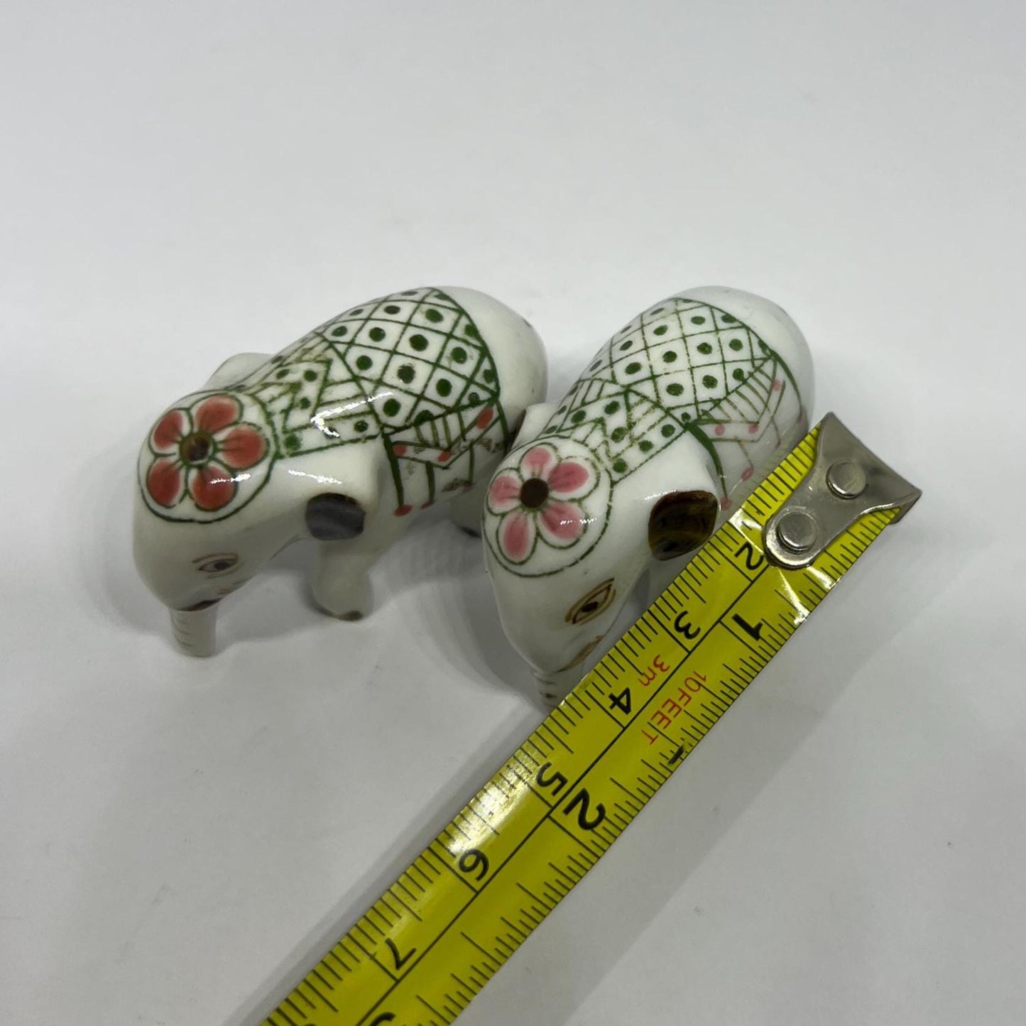 Tiny pair ceramic elephants in ceremonial dress with floral head dress.