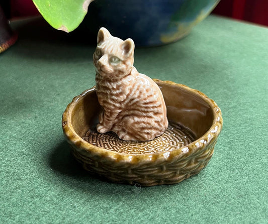 Wade tabby cat sitting in a  green basket.