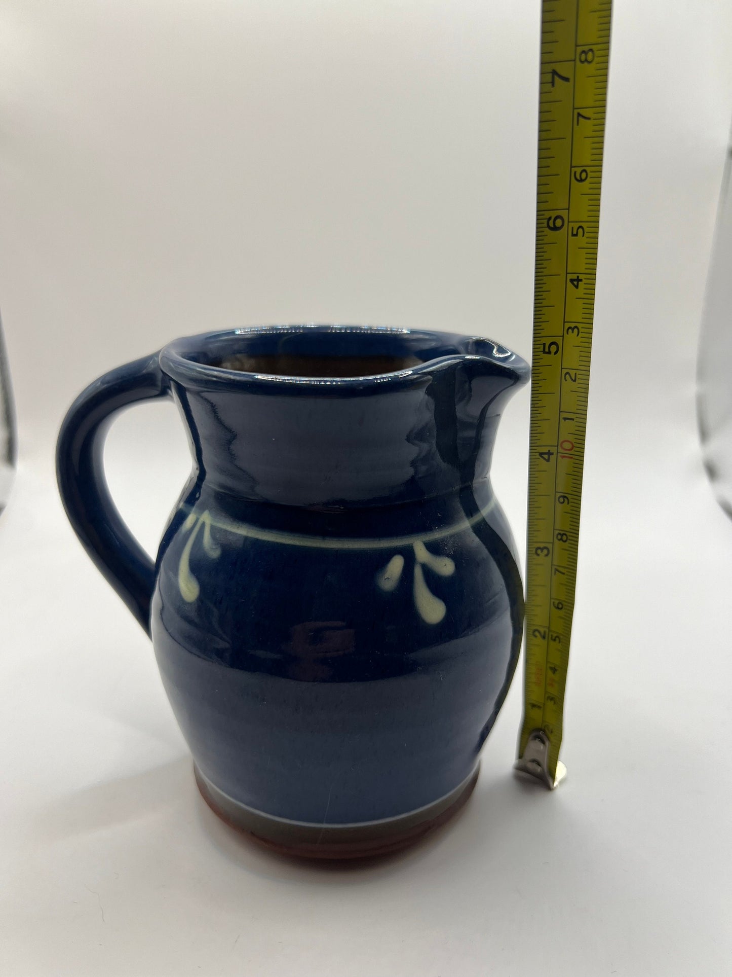 Studio pottery terracotta blue glazed milk water jug. White leaf detail.