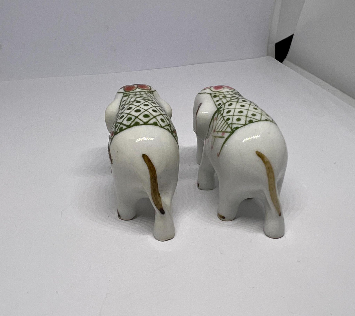 Tiny pair ceramic elephants in ceremonial dress with floral head dress.