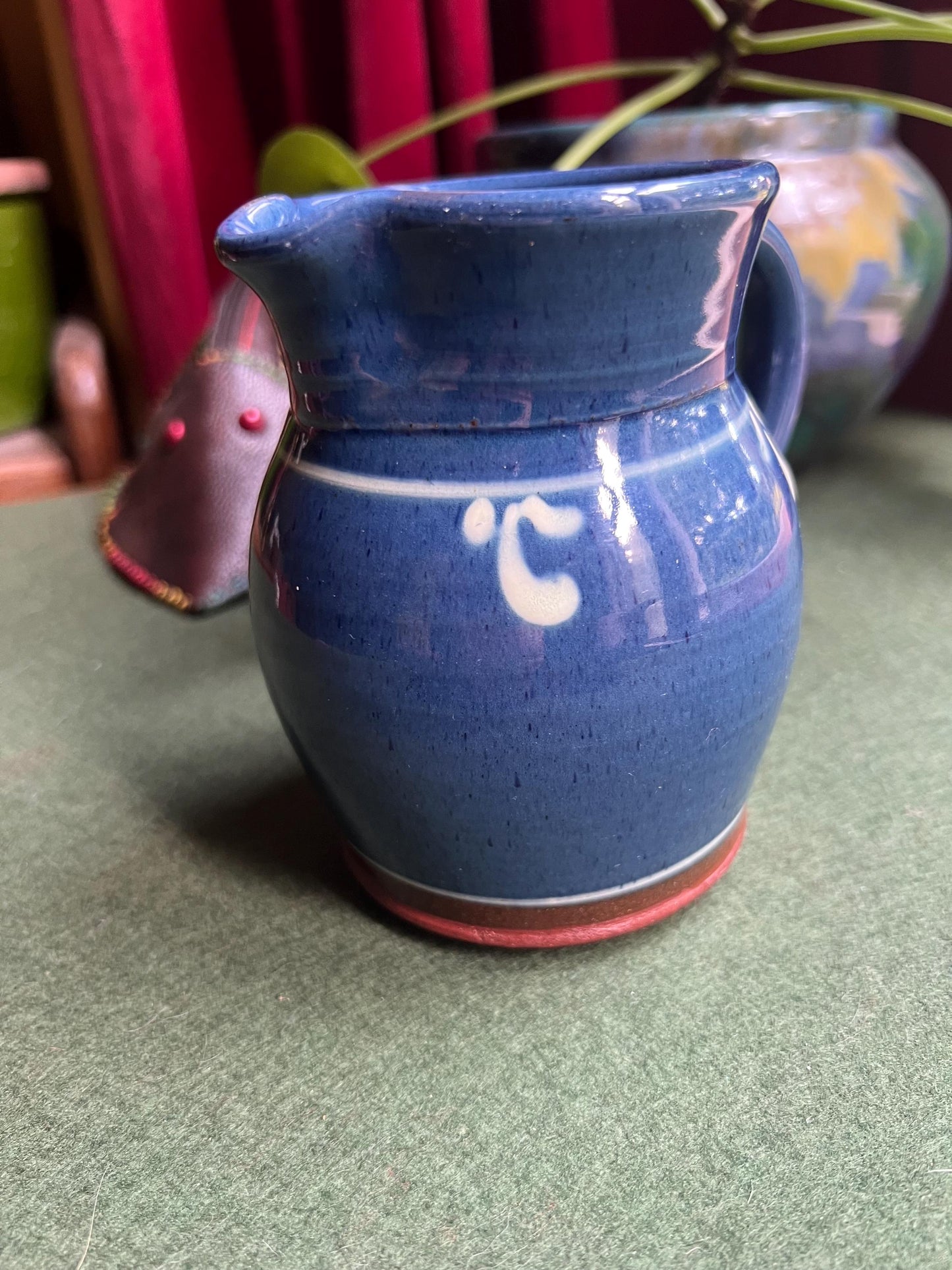 Studio pottery terracotta blue glazed milk water jug. White leaf detail.