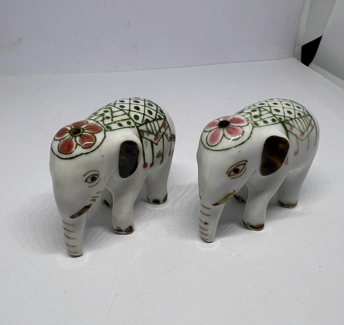 Tiny pair ceramic elephants in ceremonial dress with floral head dress.