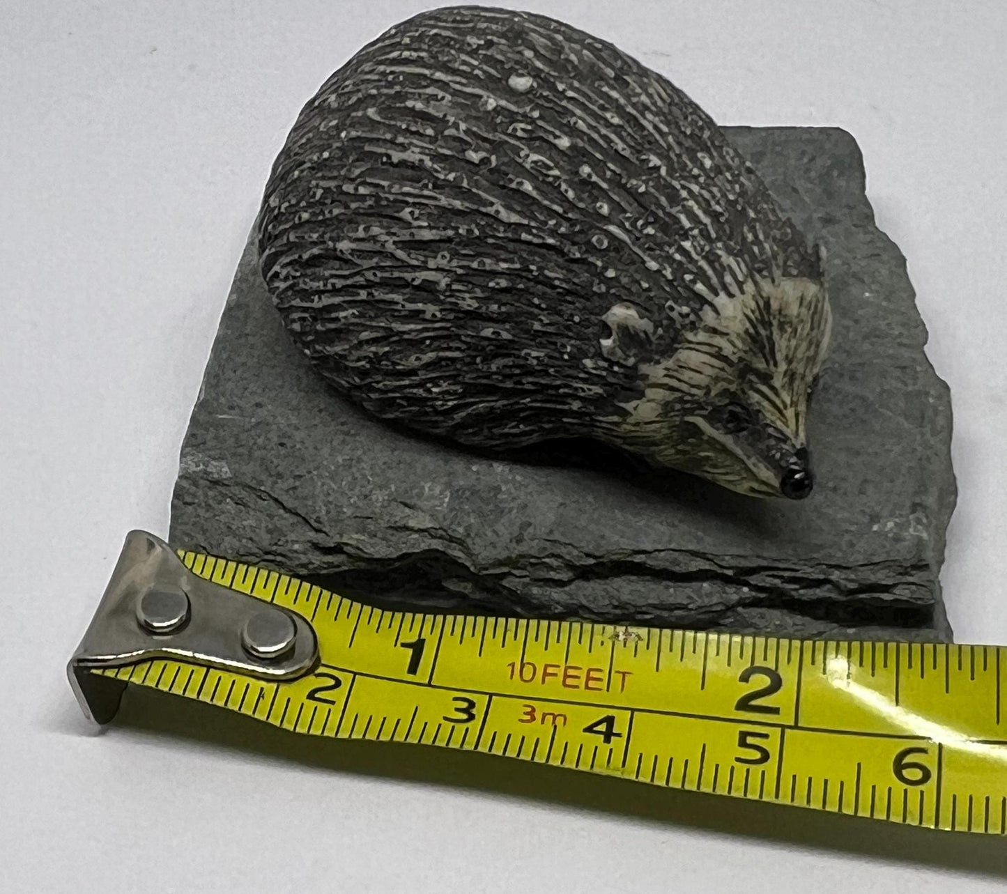 Sculpted hedgehog figurine on a slate base.