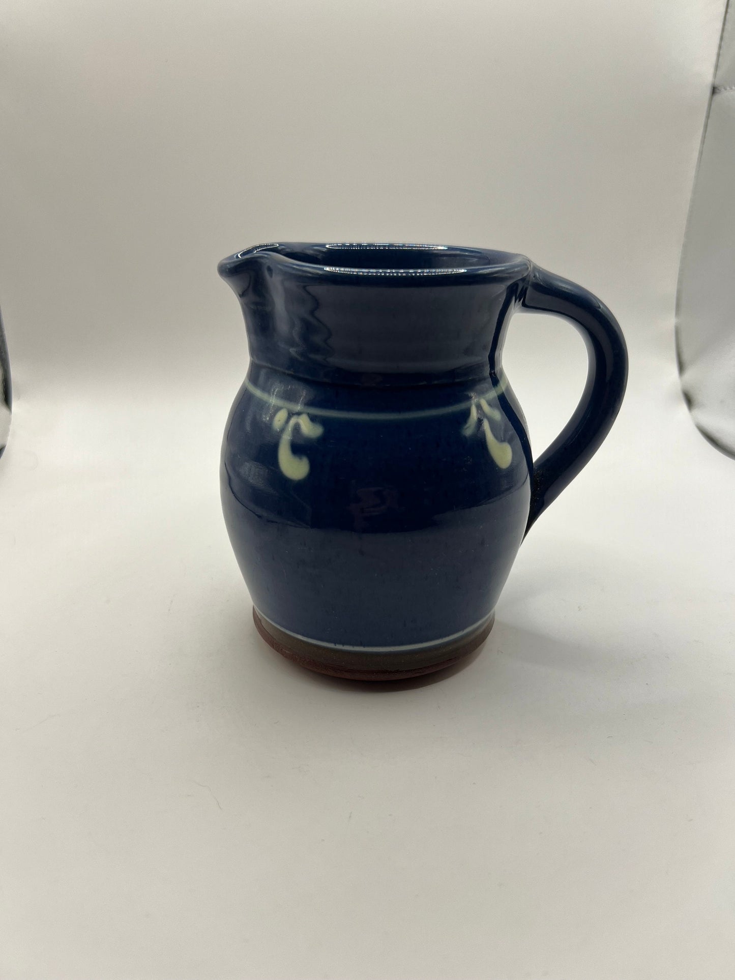 Studio pottery terracotta blue glazed milk water jug. White leaf detail.